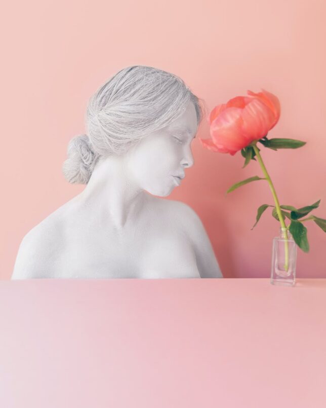 pink flower in vase near female bust